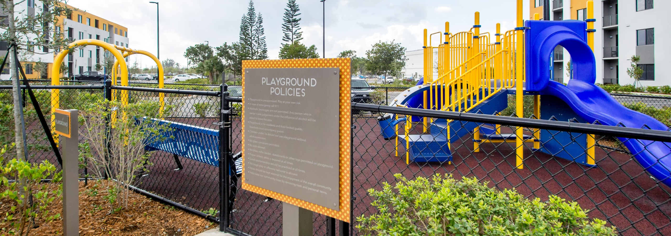 Outdoor bright yellow and blue children’s playground at AMLI 8800 featuring stairs for climbing, slide and swing set