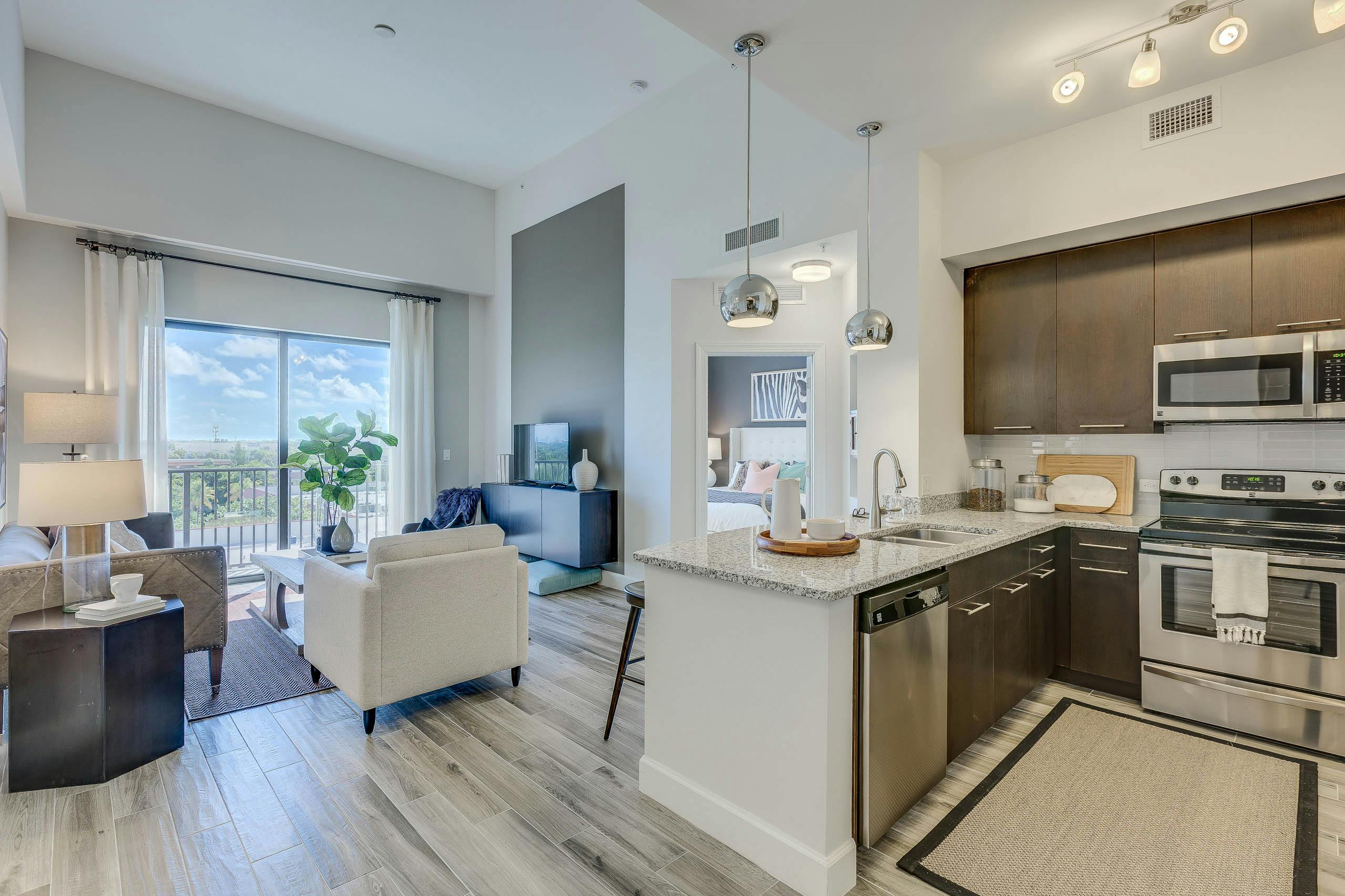 An apartment living room at AMLI Joya with white armchair and wood cabinetry, granite counters and stainless steel appliances