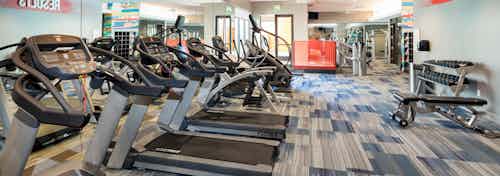 Interior close up of exercise machines in the fitness center at AMLI on Aldrich with blue and grey flooring and light walls