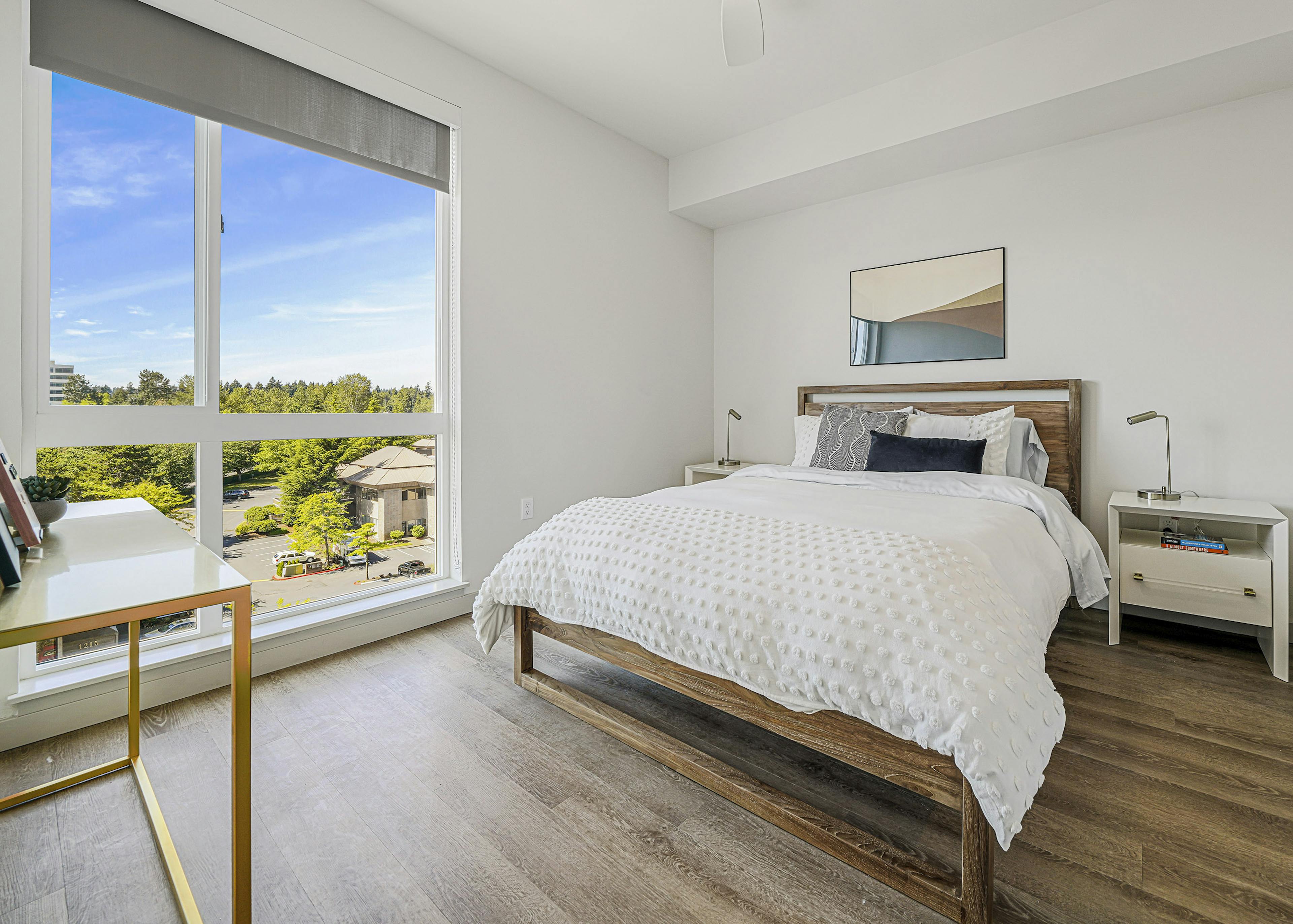 Interior view of an AMLI Spring District apartment bedroom with large window with solar shade and queen bed with nightstands