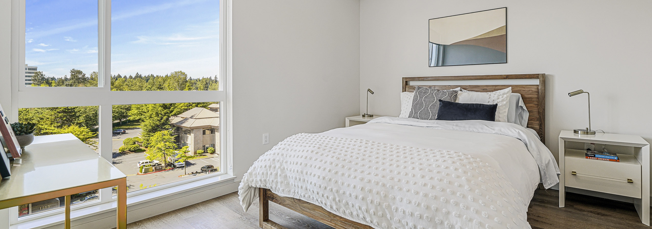 Interior view of an AMLI Spring District apartment bedroom with large window with solar shade and queen bed with nightstands