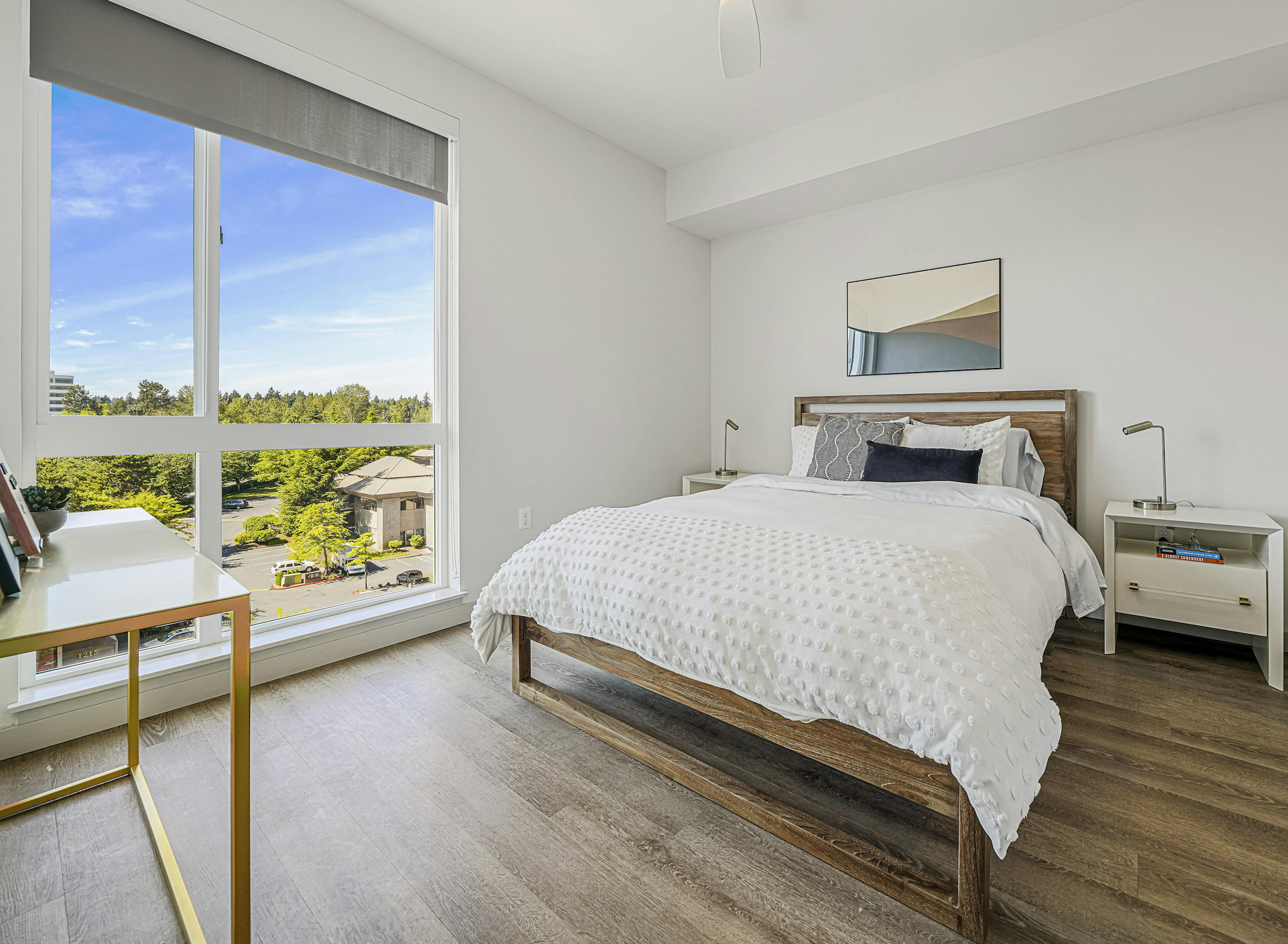 Interior view of an AMLI Spring District apartment bedroom with large window with solar shade and queen bed with nightstands