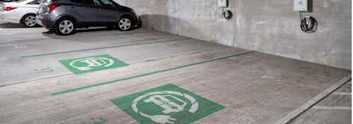 Electric car charging station in the parking garage at AMLI Buckhead with grey and white cars parked in the background