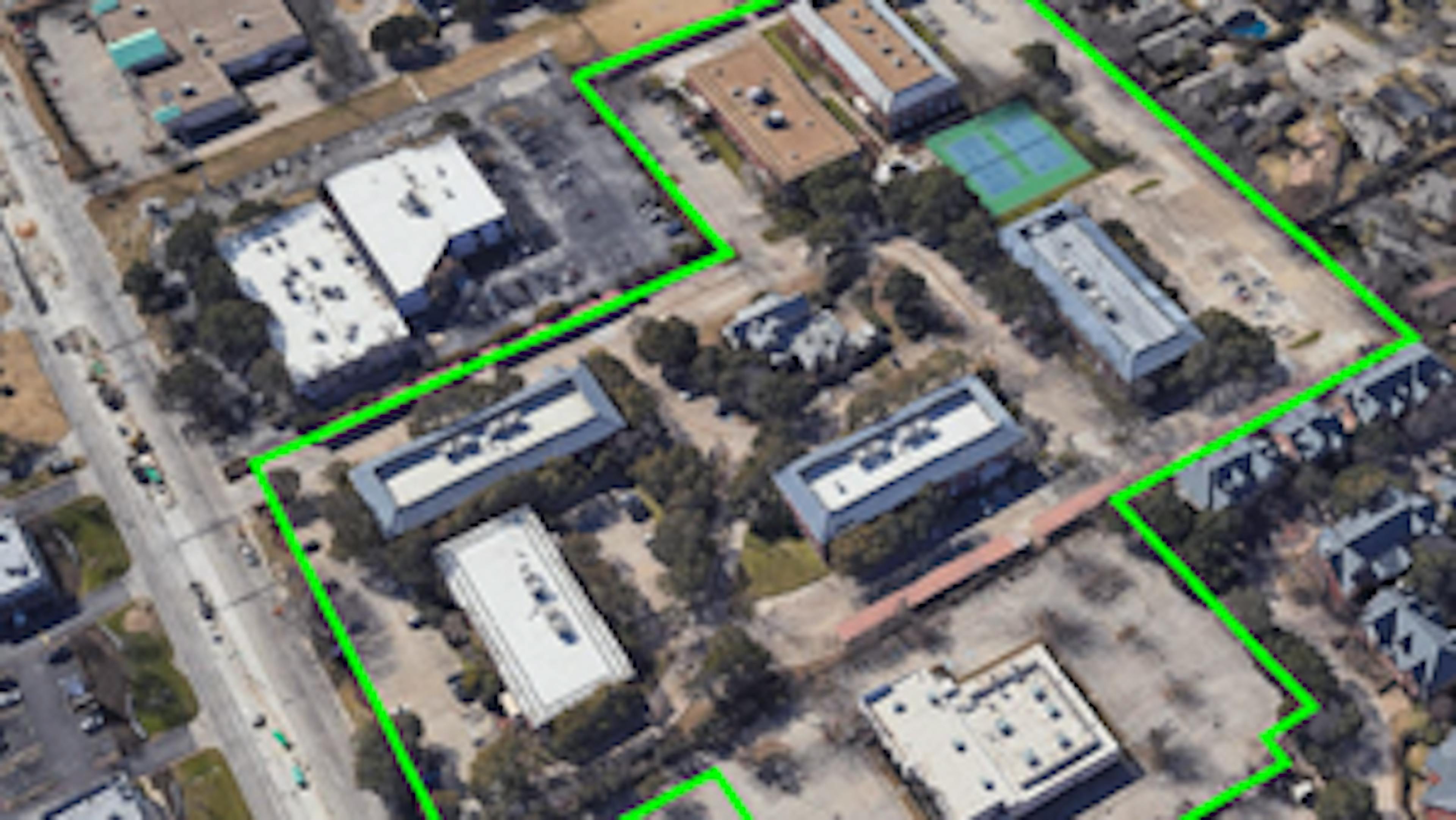 Aerial view of land purchased for AMLI Tree House apartments with buildings and a bright green outline showing parcel 
