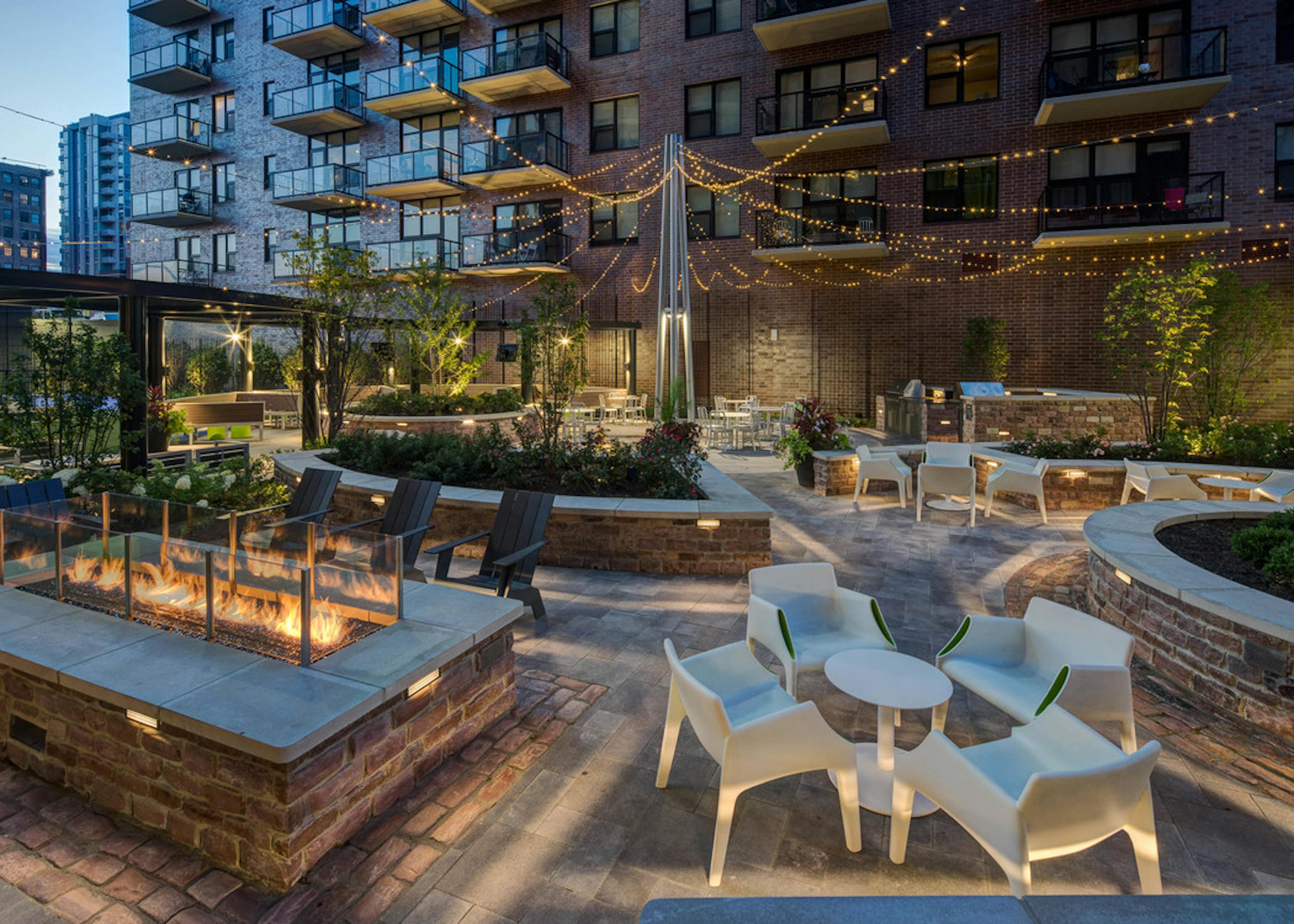 Exterior view of the courtyard lounge at the AMLI Lofts apartment community at night with city buildings visible in the back