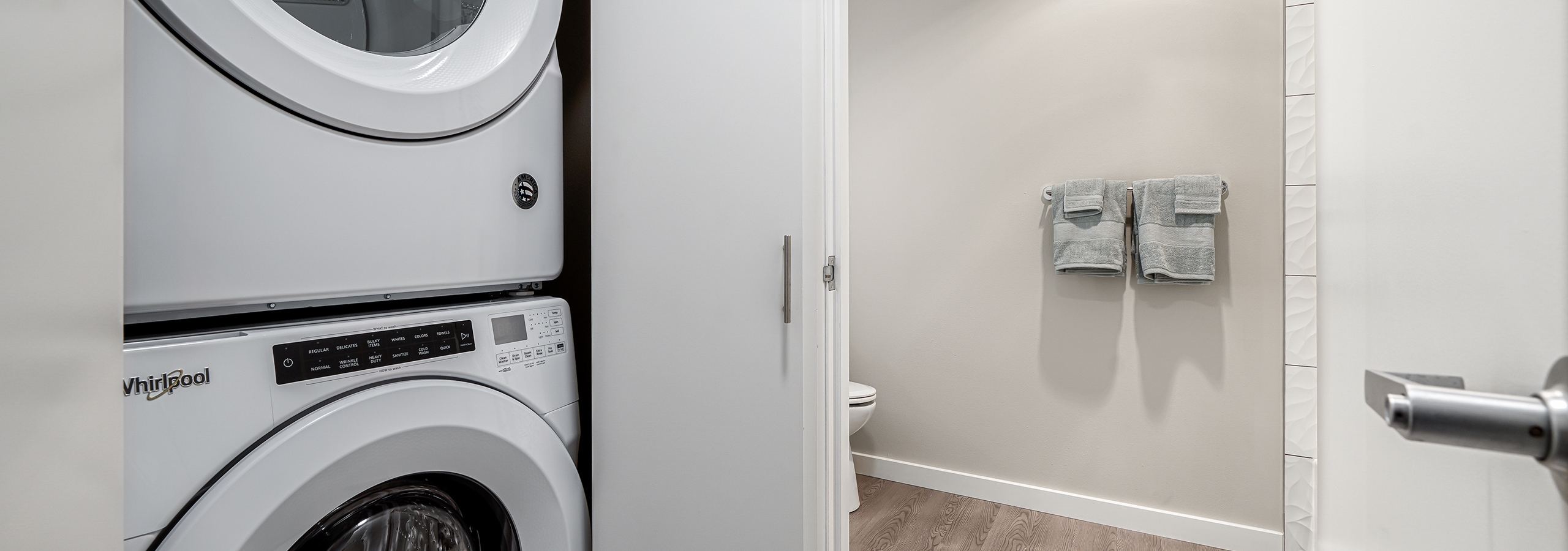 White stackable washer and dryer in closet with folding doors and view of bathroom at AMLI Bellevue Park apartments