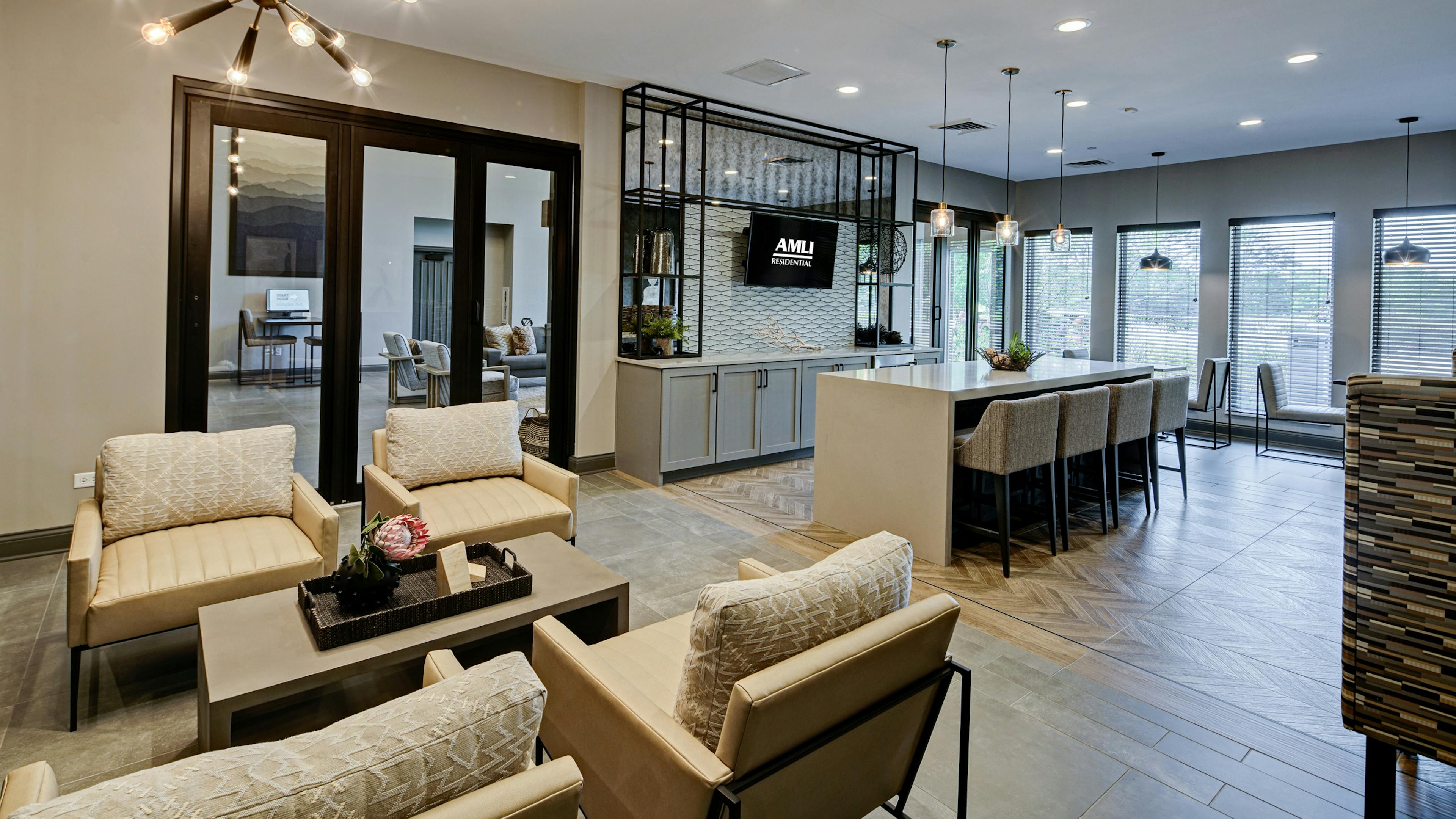 AMLI at Seven Bridges resident lounge with several seating areas including serving bar with 4 stools facing mounted TV 
