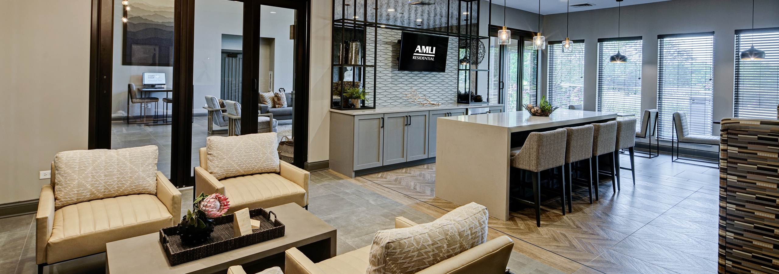 AMLI at Seven Bridges resident lounge with several seating areas including serving bar with 4 stools facing mounted TV
