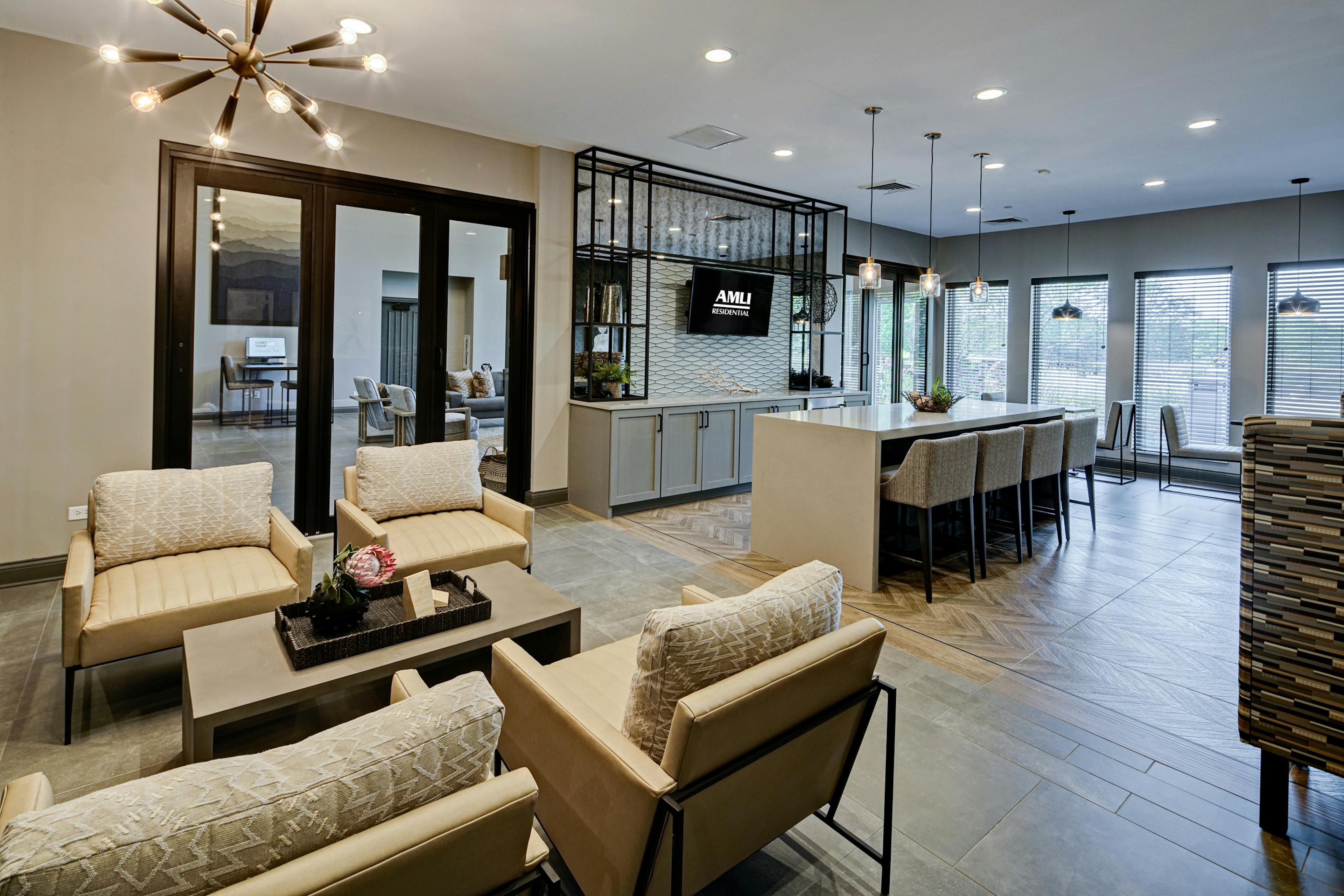 AMLI at Seven Bridges resident lounge with several seating areas including serving bar with 4 stools facing mounted TV 