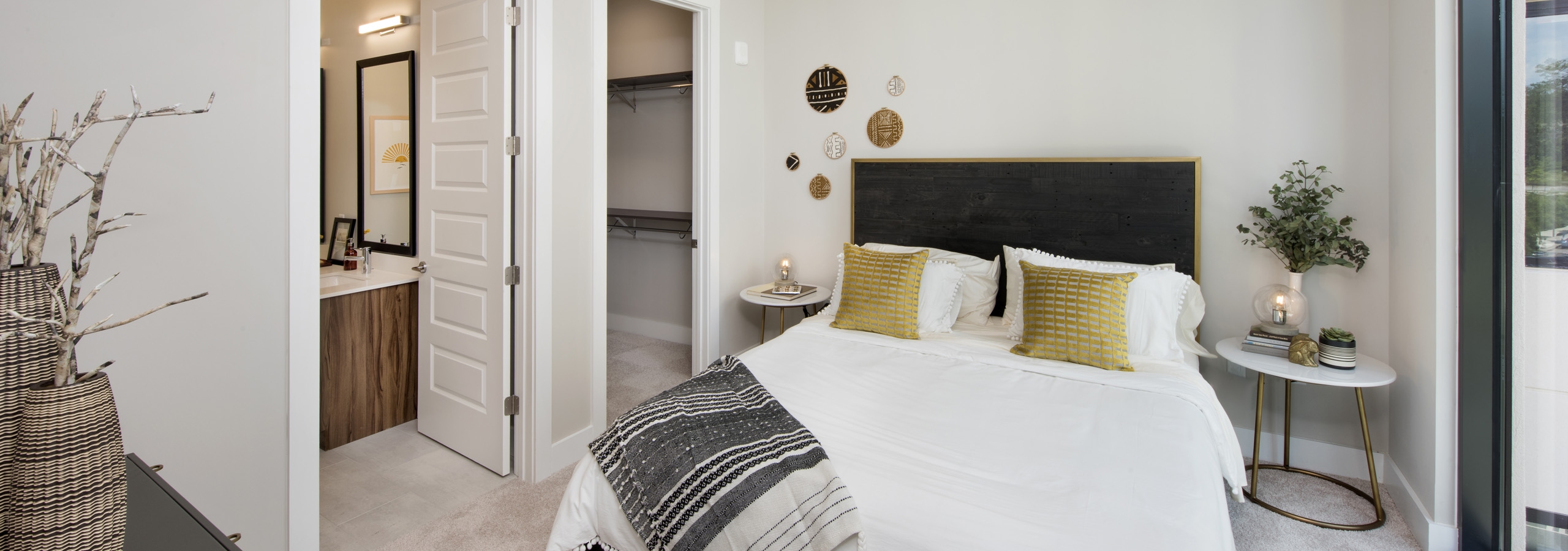 AMLI Lenox bedroom with floor to ceiling window and a bed with a white comforter and bedside nightstands and walk in closet