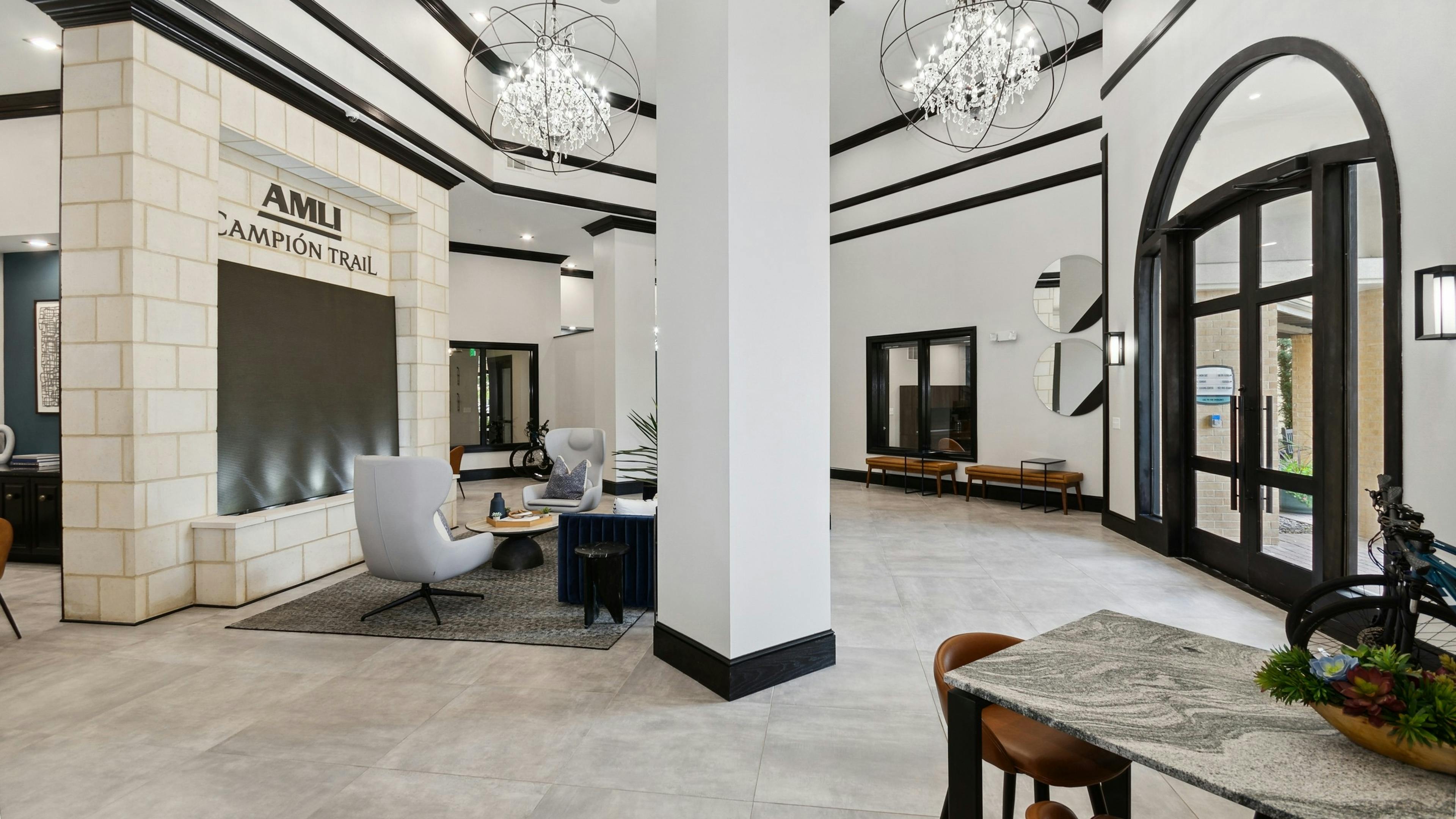 Leasing office with white walls with black trim and pillars and chandeliers and seating at AMLI Campion Trail apartments