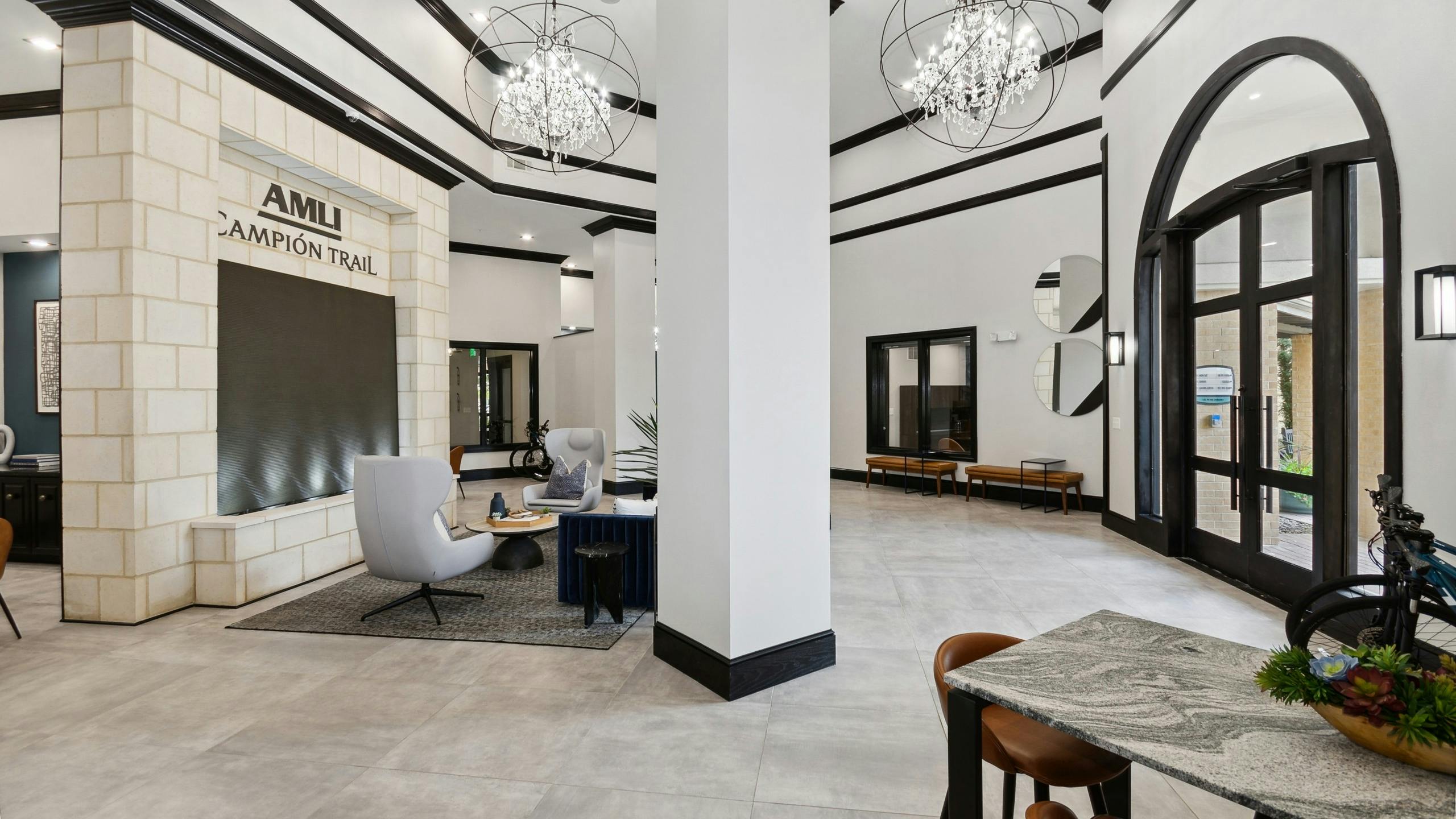 Leasing office with white walls with black trim and pillars and chandeliers and seating at AMLI Campion Trail apartments