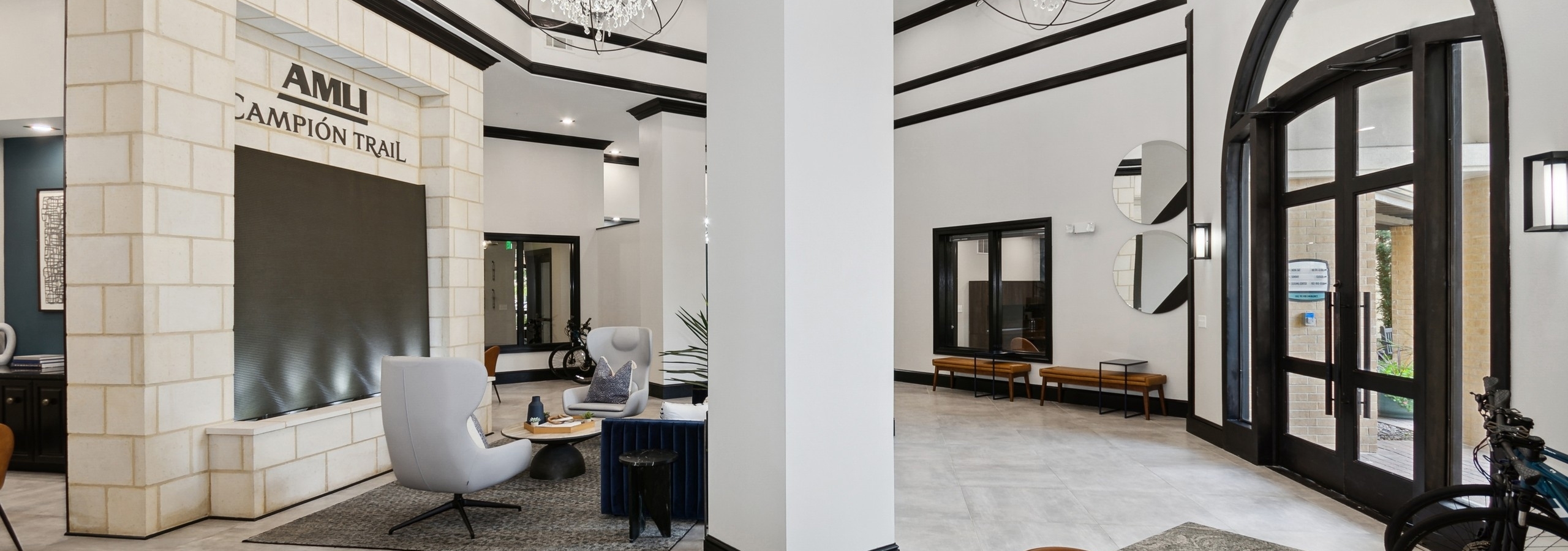 Leasing office with white walls with black trim and pillars and chandeliers and seating at AMLI Campion Trail apartments