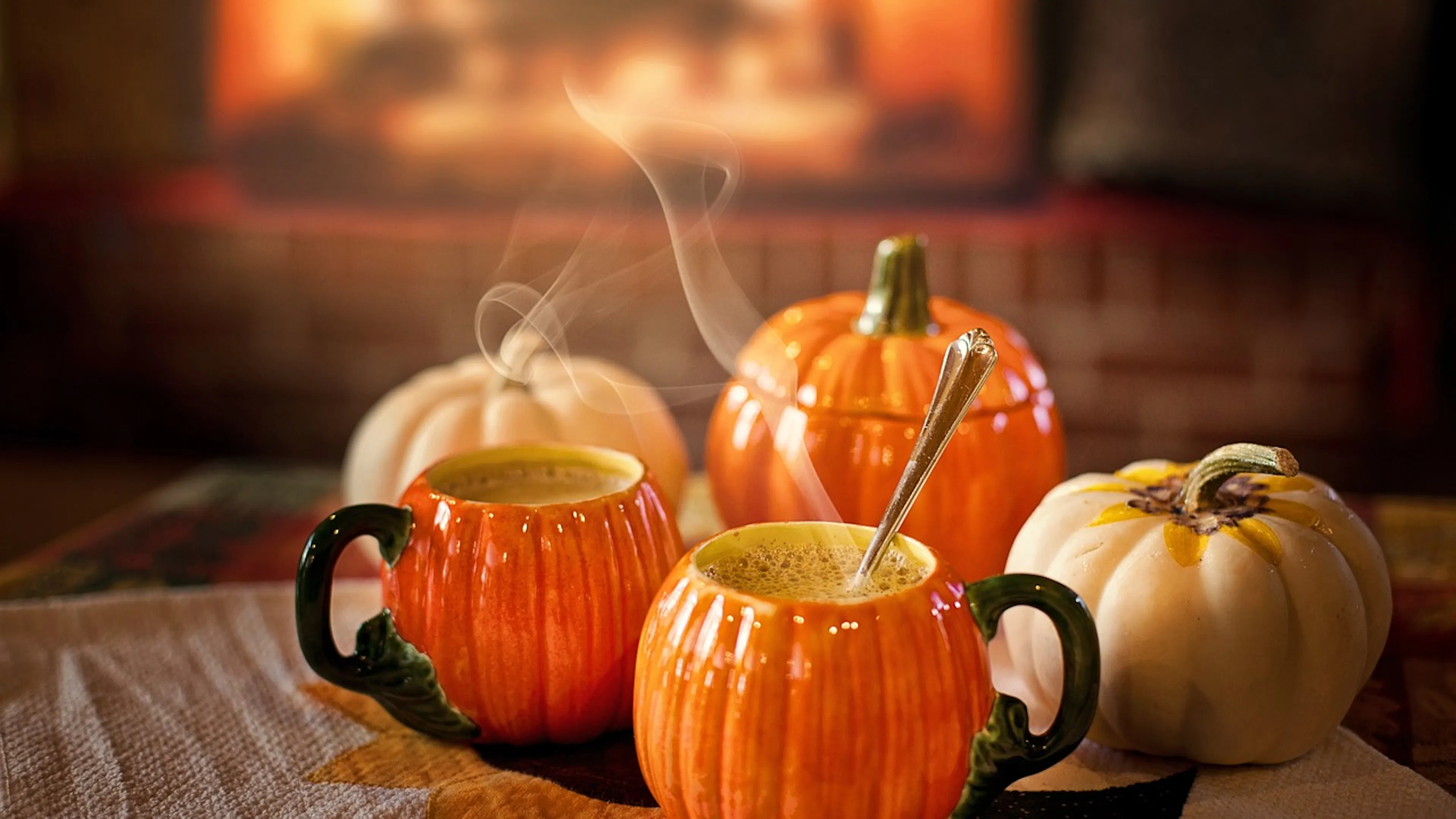 Pumpkin shaped ceramic mugs with hot coffee steaming inside them