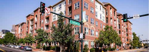 Exterior view of AMLI Park Avenue apartment building with side streets and several cars park and large trees and blue sky