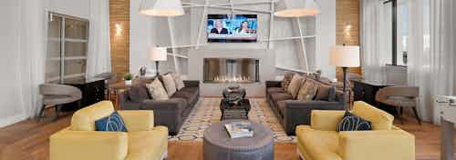 Interior view of AMLI 8800 resident lounge with entertaining seating area, yellow accent armchairs, fireplace and TV on wall