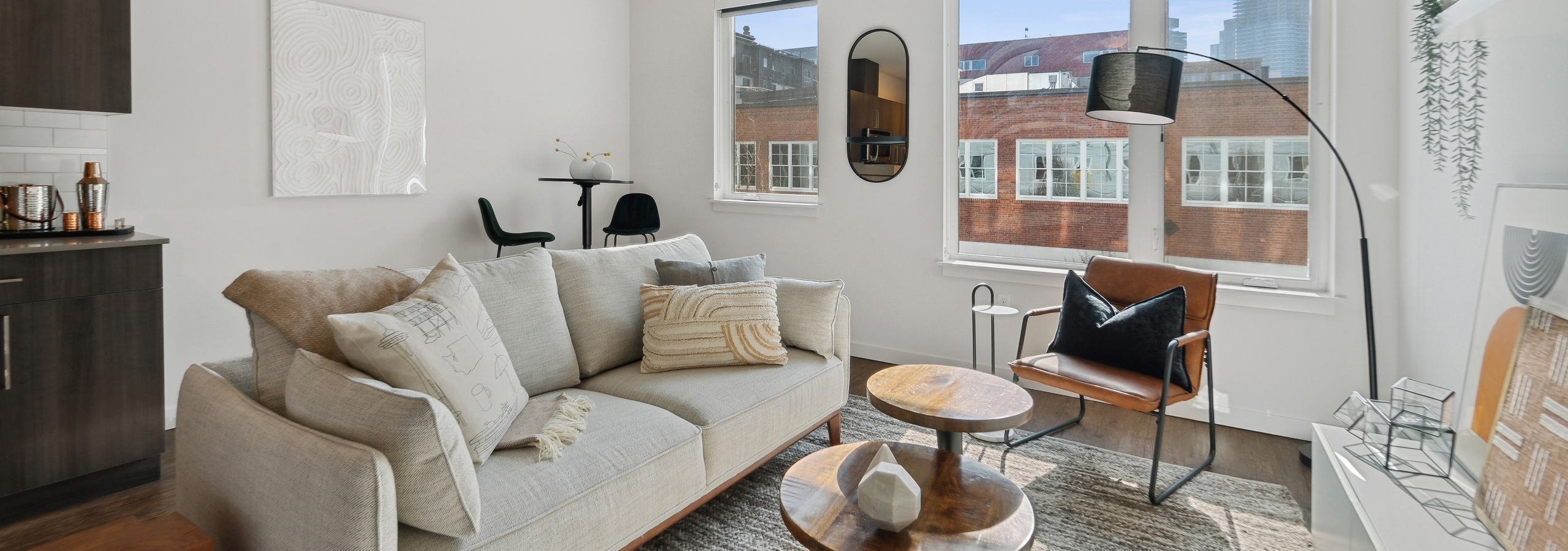 Interior view of a living room at AMLI South Lake Union apartments with a couch and coffee tables and windows with city views