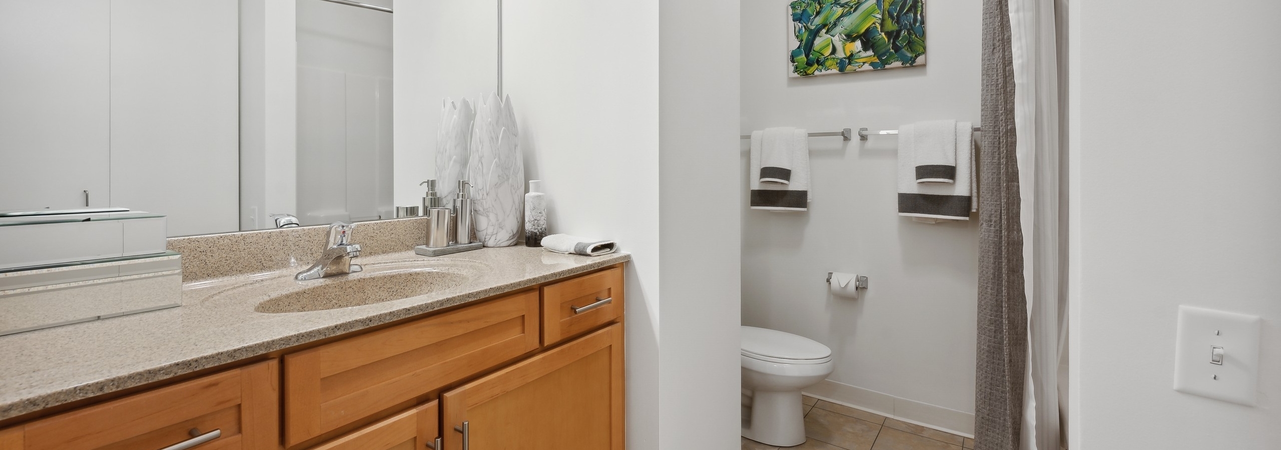 Bathroom with maple cabinets with a light tan colored countertop and tile flooring at AMLI 900 apartments