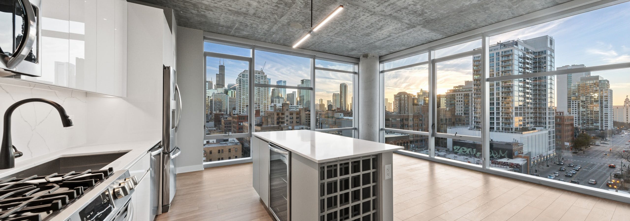 AMLI 808 modern apartment kitchen and island lined by floor to ceiling windows showing gorgeous daytime city view