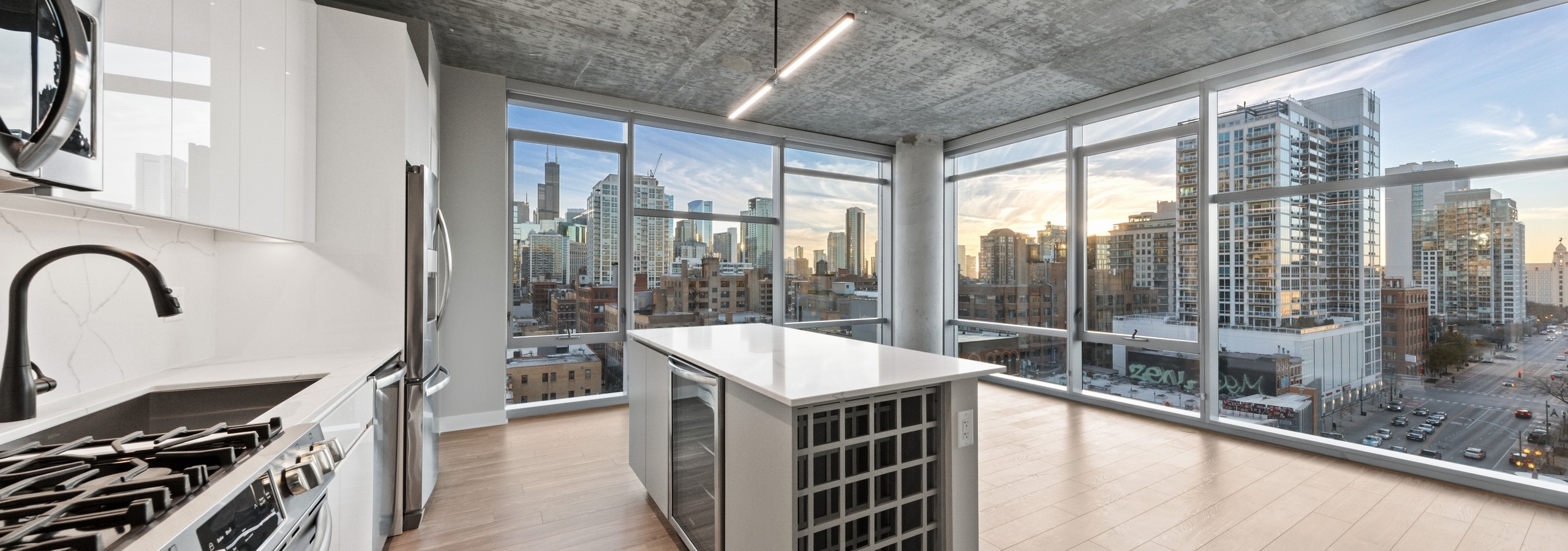AMLI 808 modern apartment kitchen and island lined by floor to ceiling windows showing gorgeous daytime city view