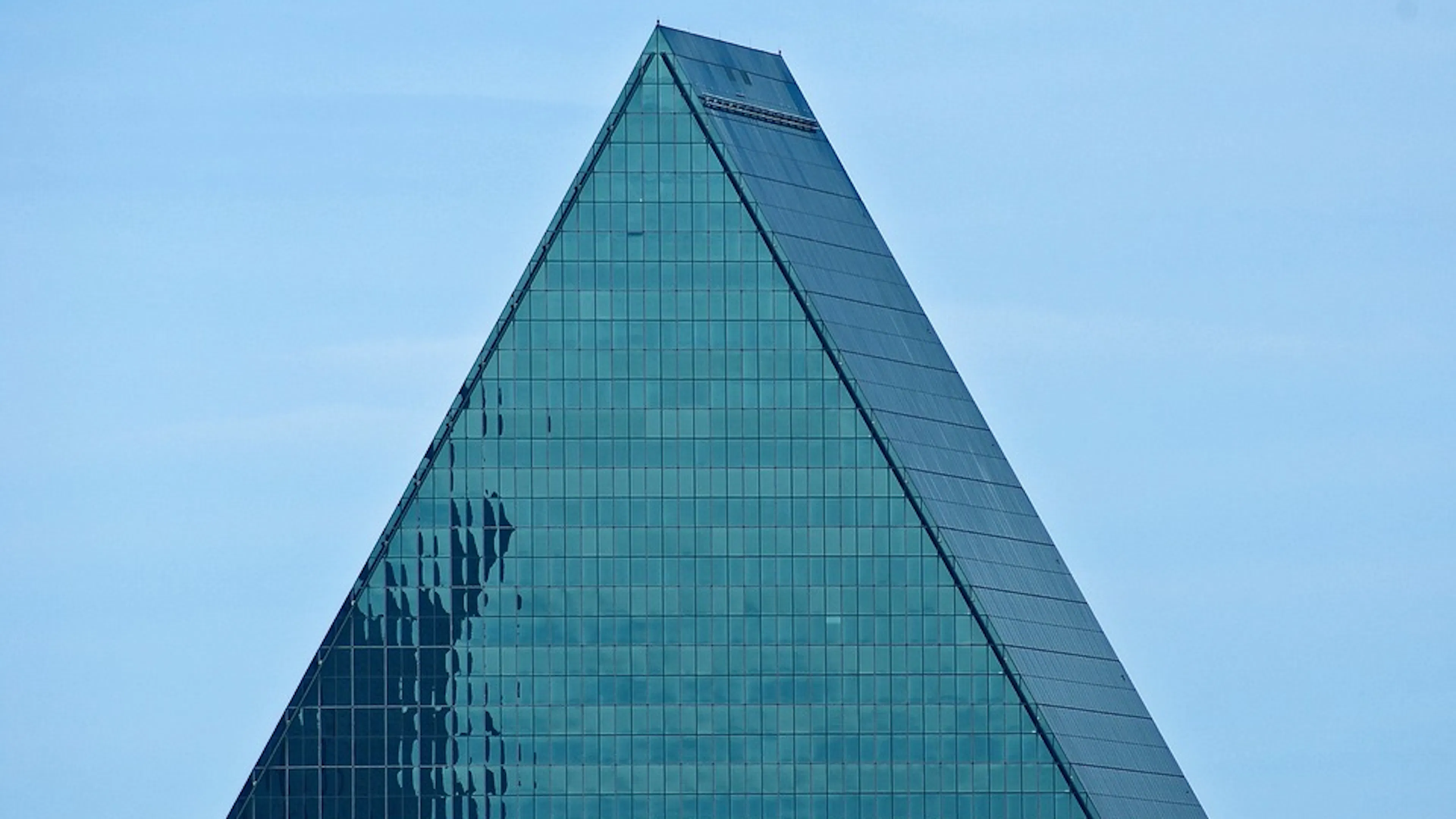 The top portion of the Fountain Place skyscraper in Dallas against a backdrop of clear sky