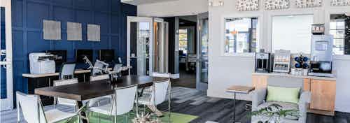 Interior view of the cyber cafe at AMLI Arista apartments with a coffee machine and table and chairs and a desk with computer