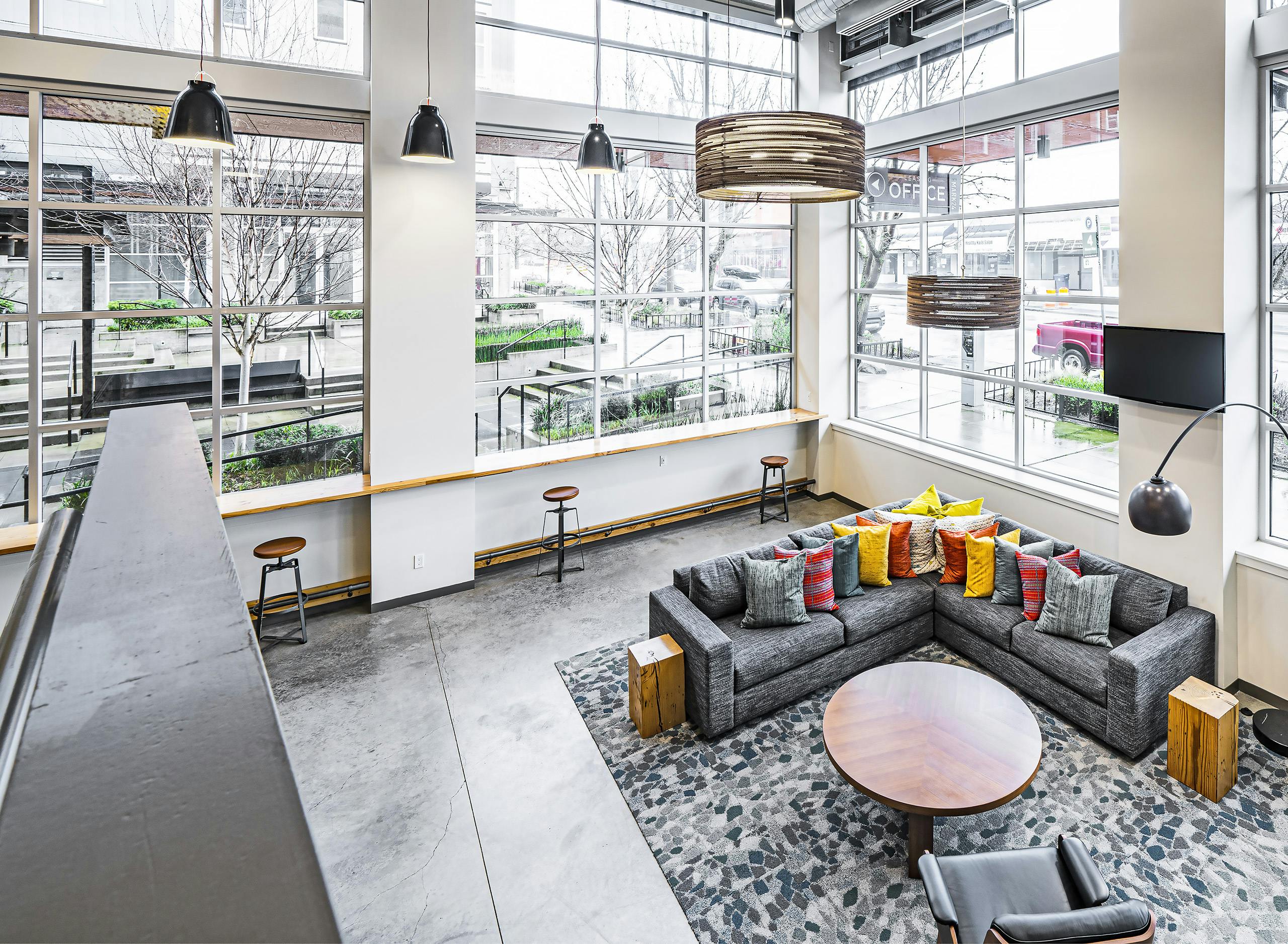 View from above of the bright lobby at AMLI Mark24 with two walks of windows and seating area with colorful pillow