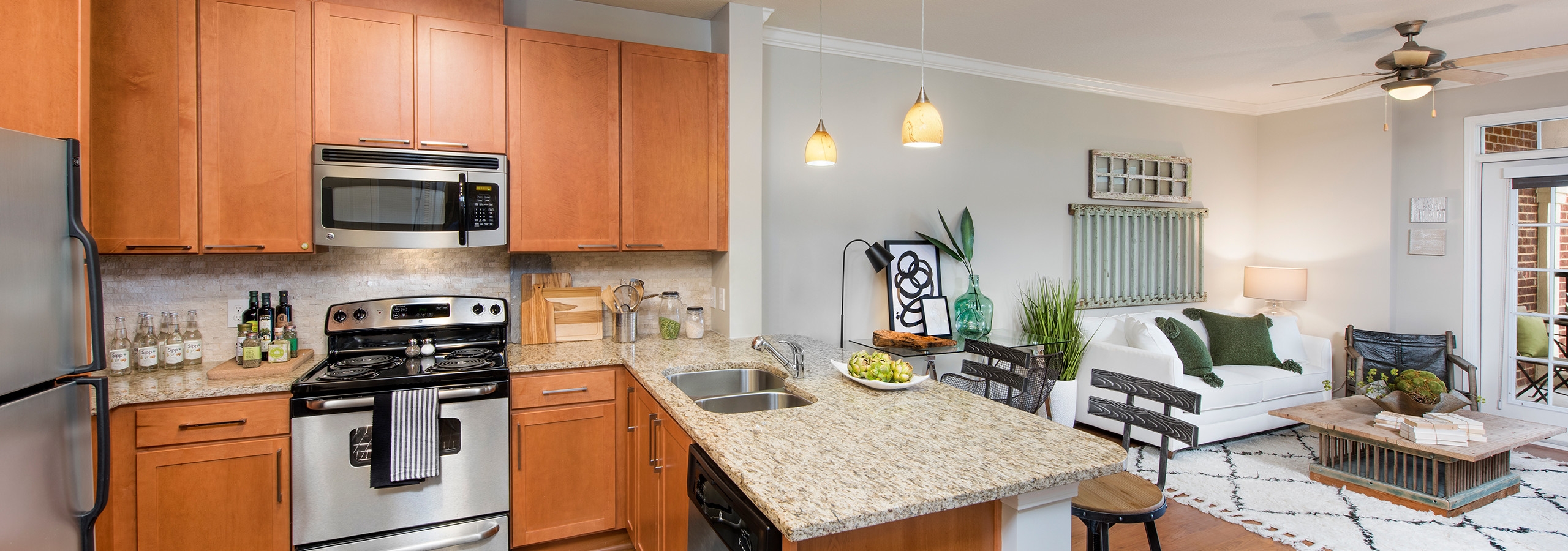 Interior of AMLI North Point kitchen with granite countertops and barstools at a counter which connects to living area