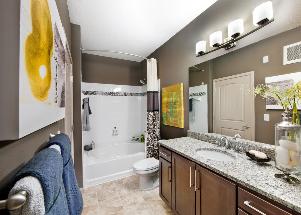 AMLI North Point bathroom with brown walls and white and yellow decor with a large vanity and white tiled bathtub