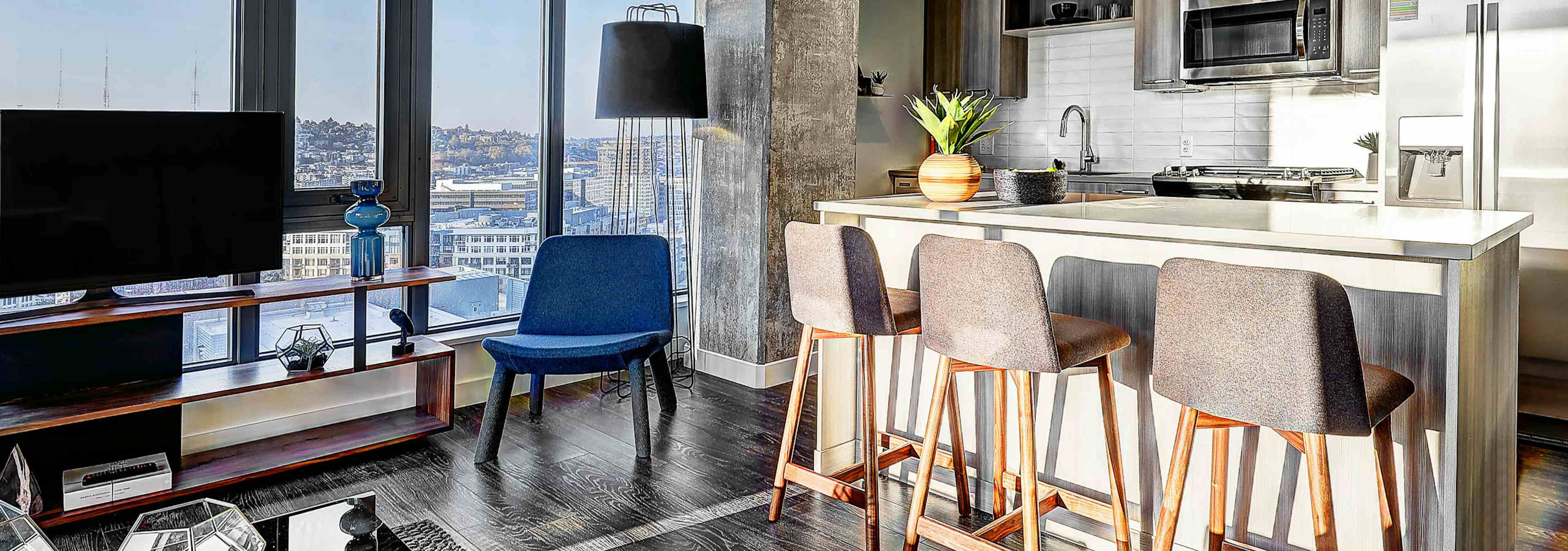 Interior view of apartment of AMLI Arc of kitchen with island with white quartz counter tops and living room and large window