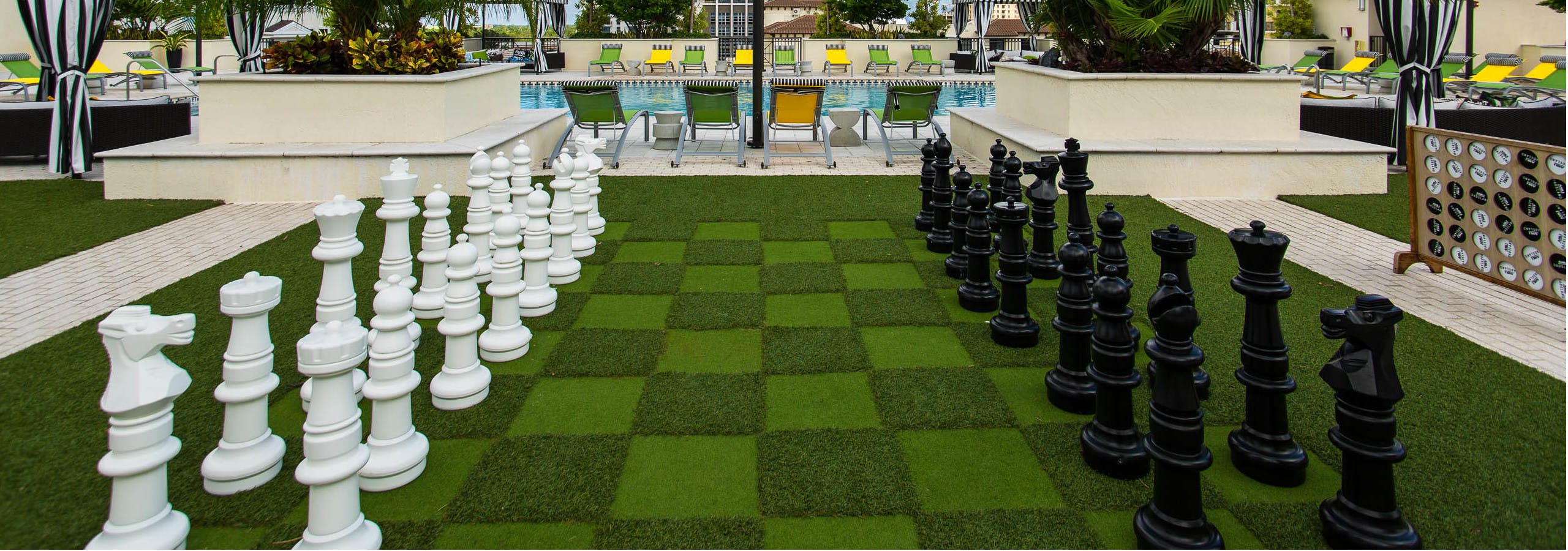Game view of AMLI Dadeland Rooftop with life sized chess game and a view of the pool and lounge chairs
