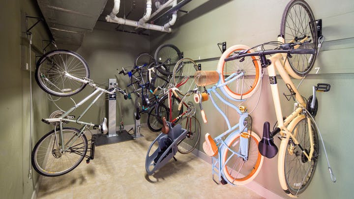 Bike storage area at AMLI at Mueller with bikes hanging vertically on light walls with an air pump for wheels in background