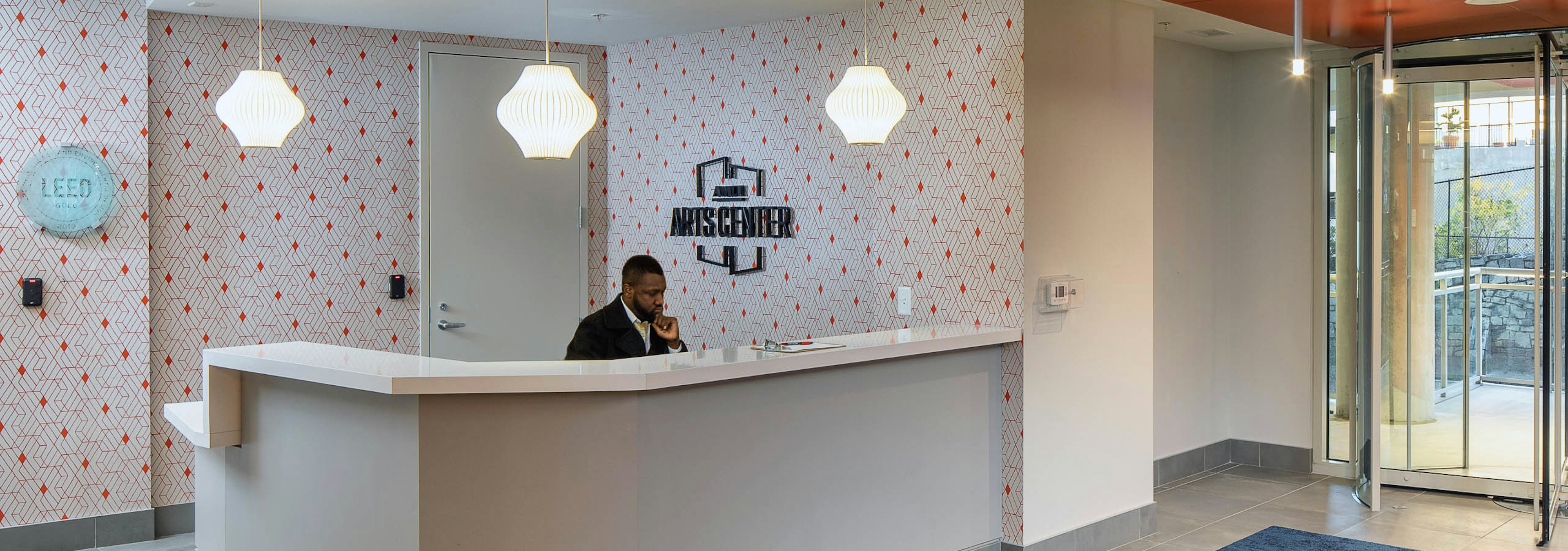 Lobby at AMLI Arts Center with white and orange patterned wallpaper and a white desk with dangling octagonal light fixtures