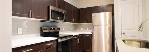Redesigned kitchen interior at AMLI Inverness apartments with view of stainless steel kitchen sink and gray tile back splash