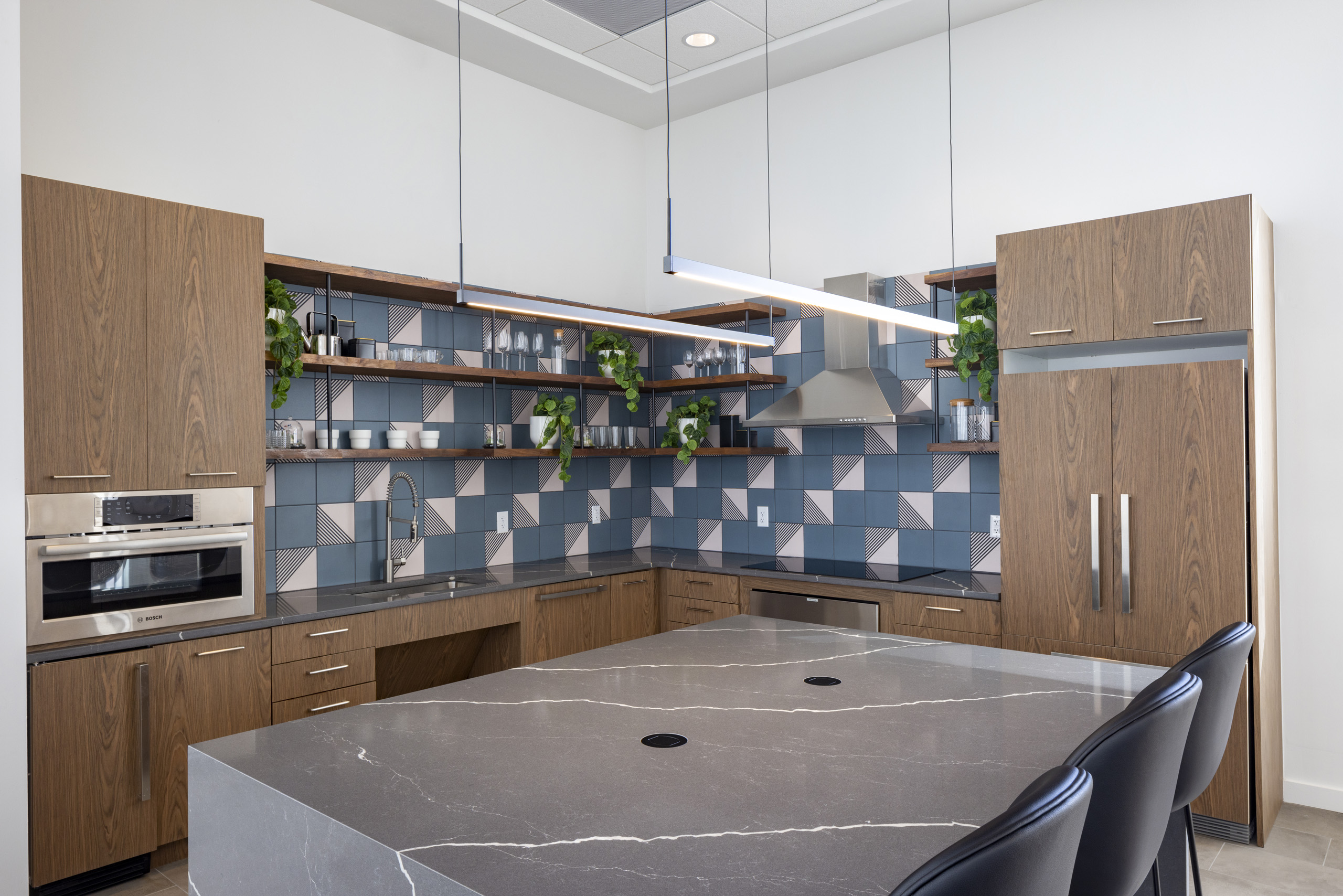 AMLI on 2nd resident lounge kitchen with geometric blue backsplash against dark modern cabinetry and sleek grey countertops 