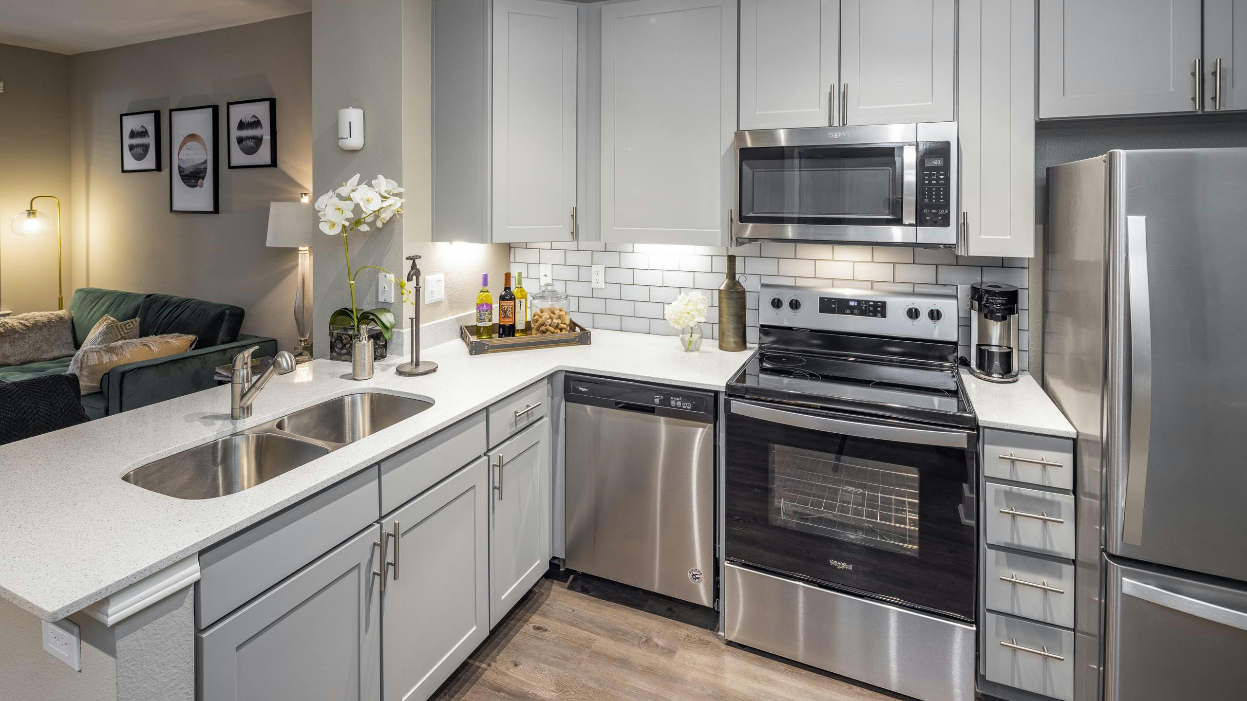 Kitchen at AMLI Eastside apartments with gray cabinets and white quartz countertops and stainless steel appliances