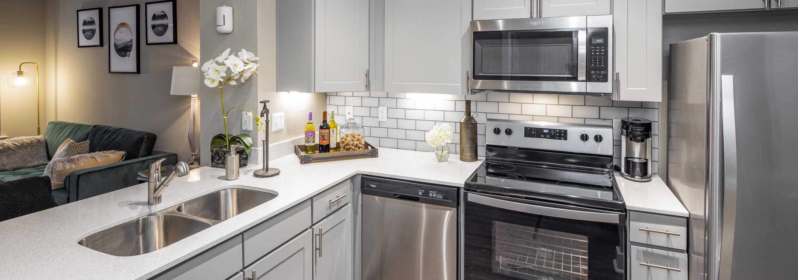 Kitchen at AMLI Eastside apartments with gray cabinets and white quartz countertops and stainless steel appliances