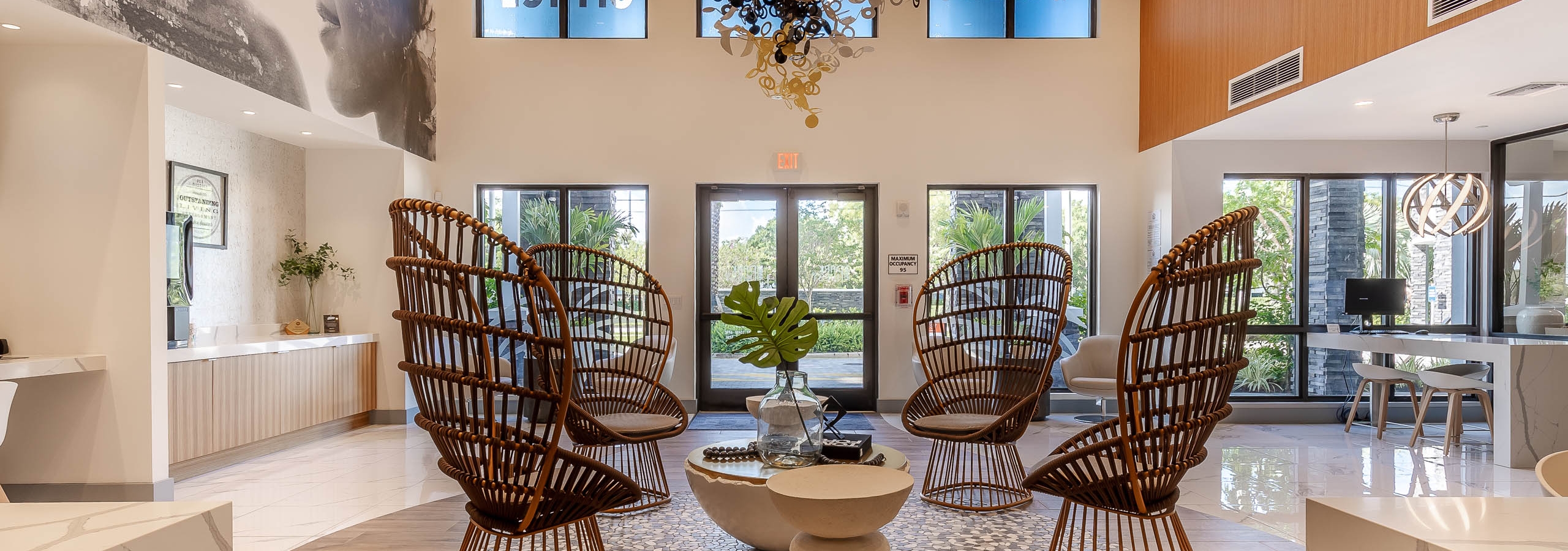 The lobby at AMLI Park West apartments with rattan armchairs and round coffee table with O shaped chandelier and wall mural