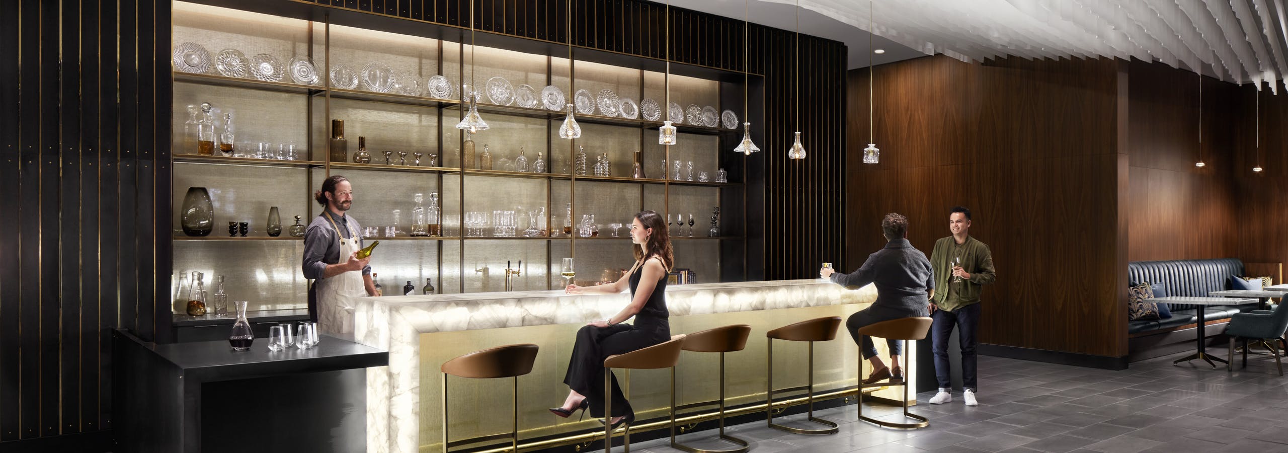A group of AMLI Fountain Place residents enjoying community bar area with an illuminated counter and hanging lights