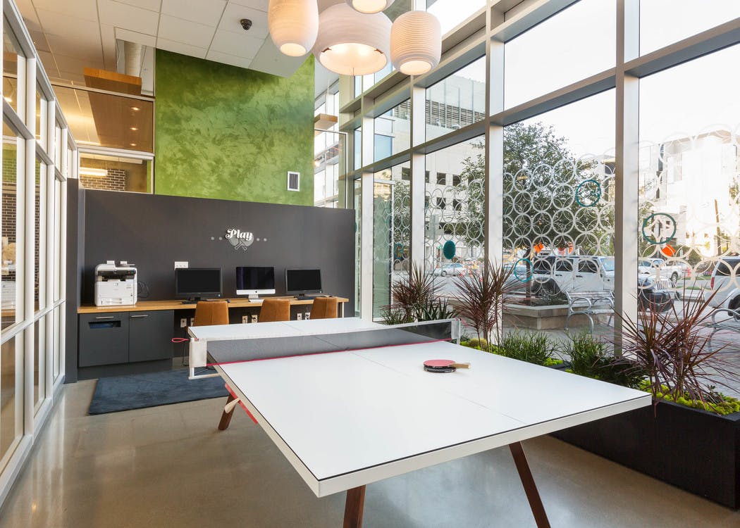 Business center at AMLI on 2nd with a long white table and wooden desk area with three computers and a printer in background