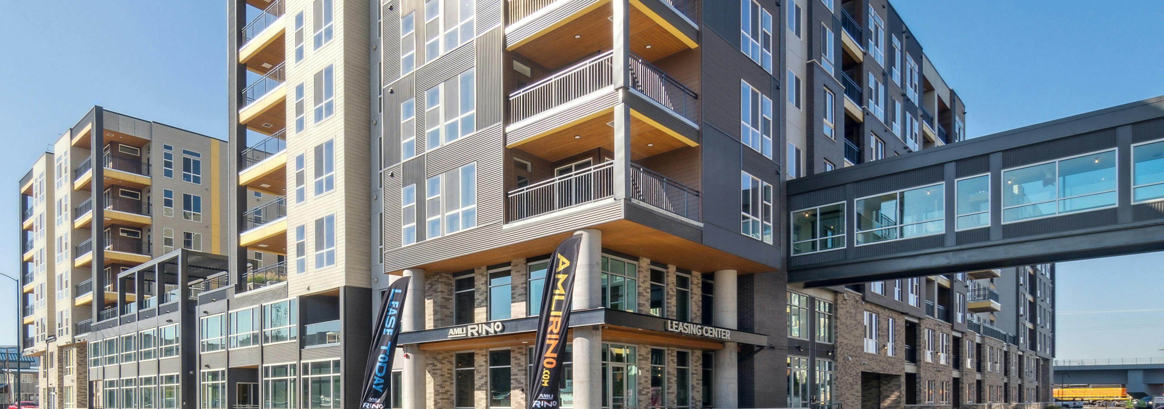 Exterior building view of AMLI RiNo with enclosed walkway and patios balconies with yellow ceilings and white and brown siding