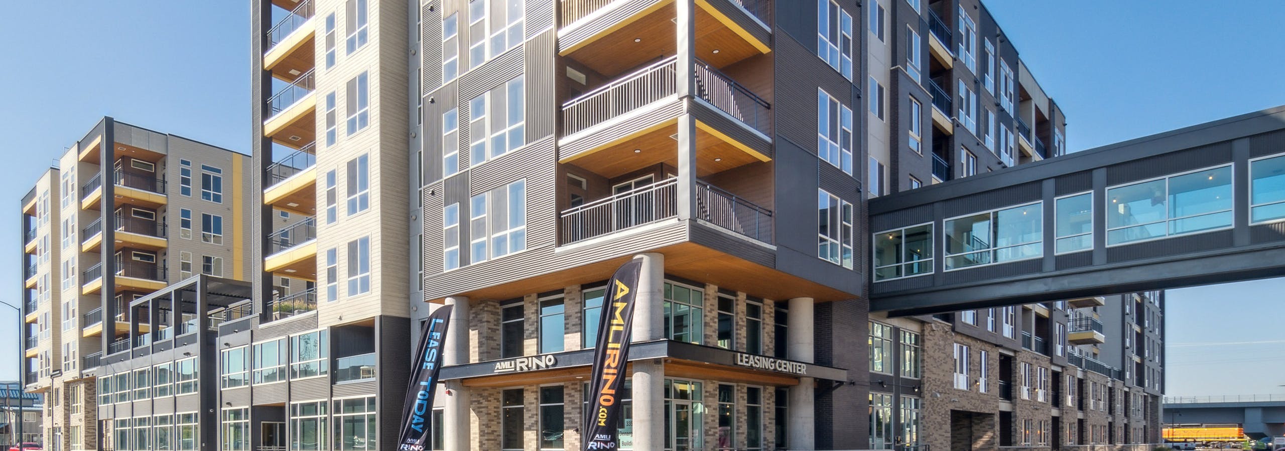 Exterior building view of AMLI RiNo with enclosed walkway and patios balconies with yellow ceilings and white and brown siding