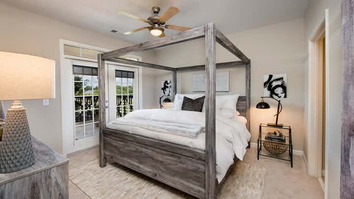 Bedroom at AMLI North Point with french doors leading outside and rustic styled decor with a canopy framed bed