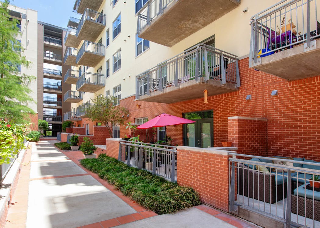 Daytime courtyard view of AMLI Downtown red brick facade with view of courtyard and thriving green trees and shrubbery