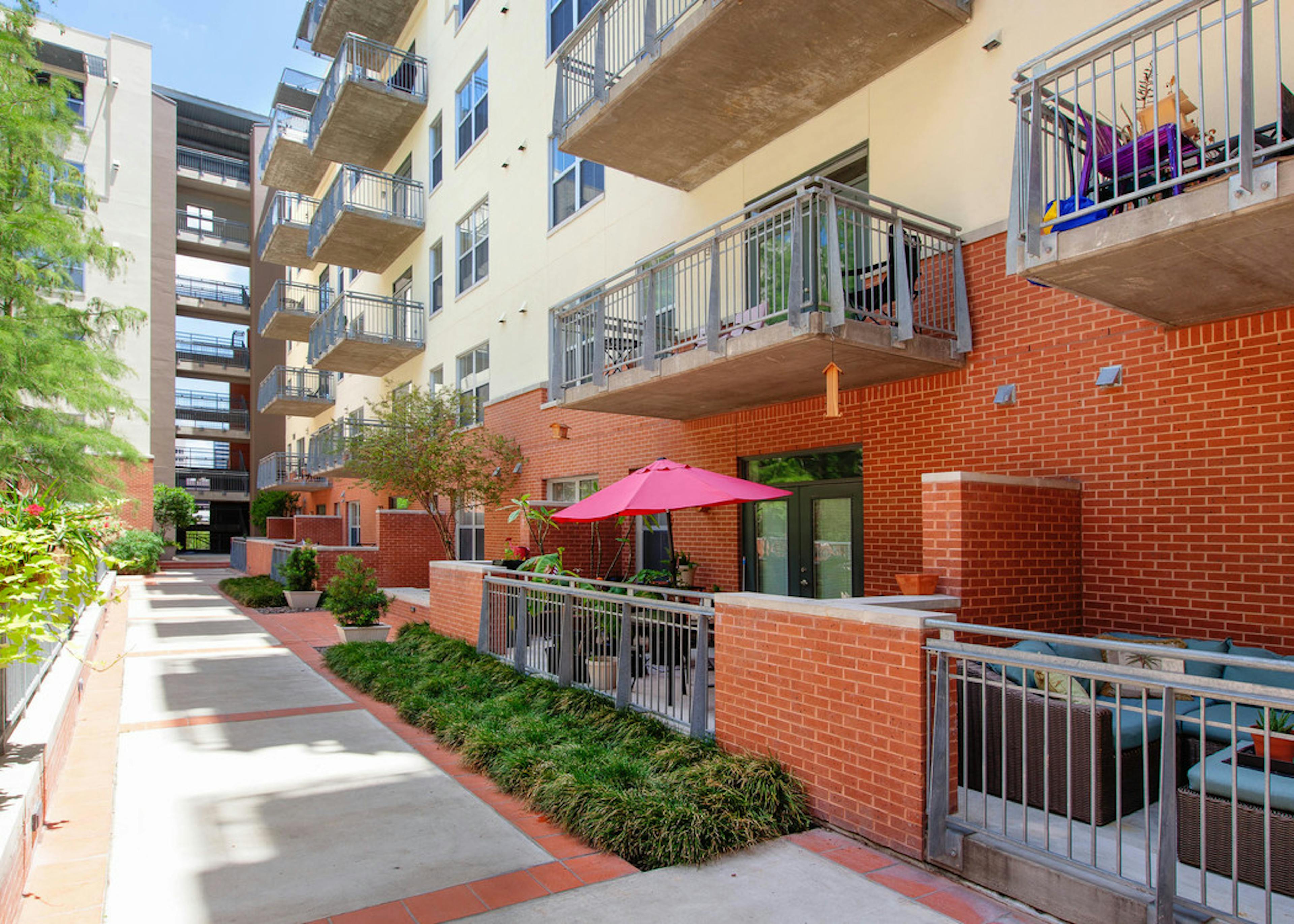 Daytime courtyard view of AMLI Downtown red brick facade with view of courtyard and thriving green trees and shrubbery