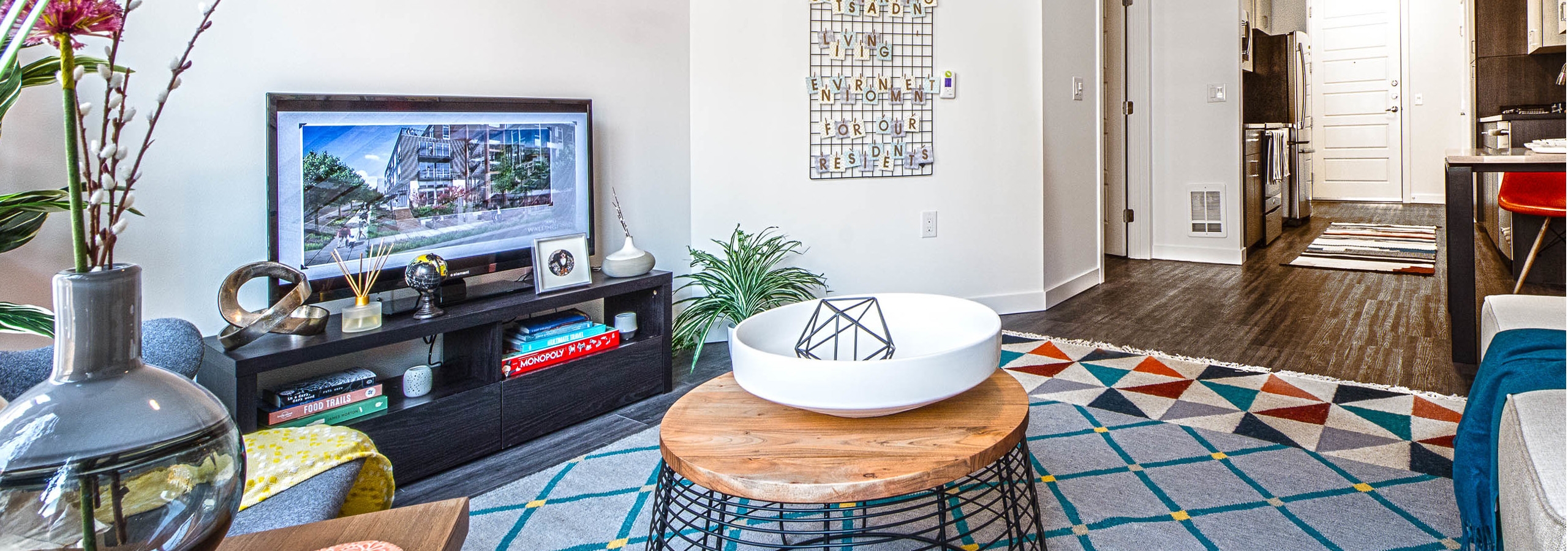 Interior view of a living room at AMLI Wallingford with TV view of kitchen with colorful carpets