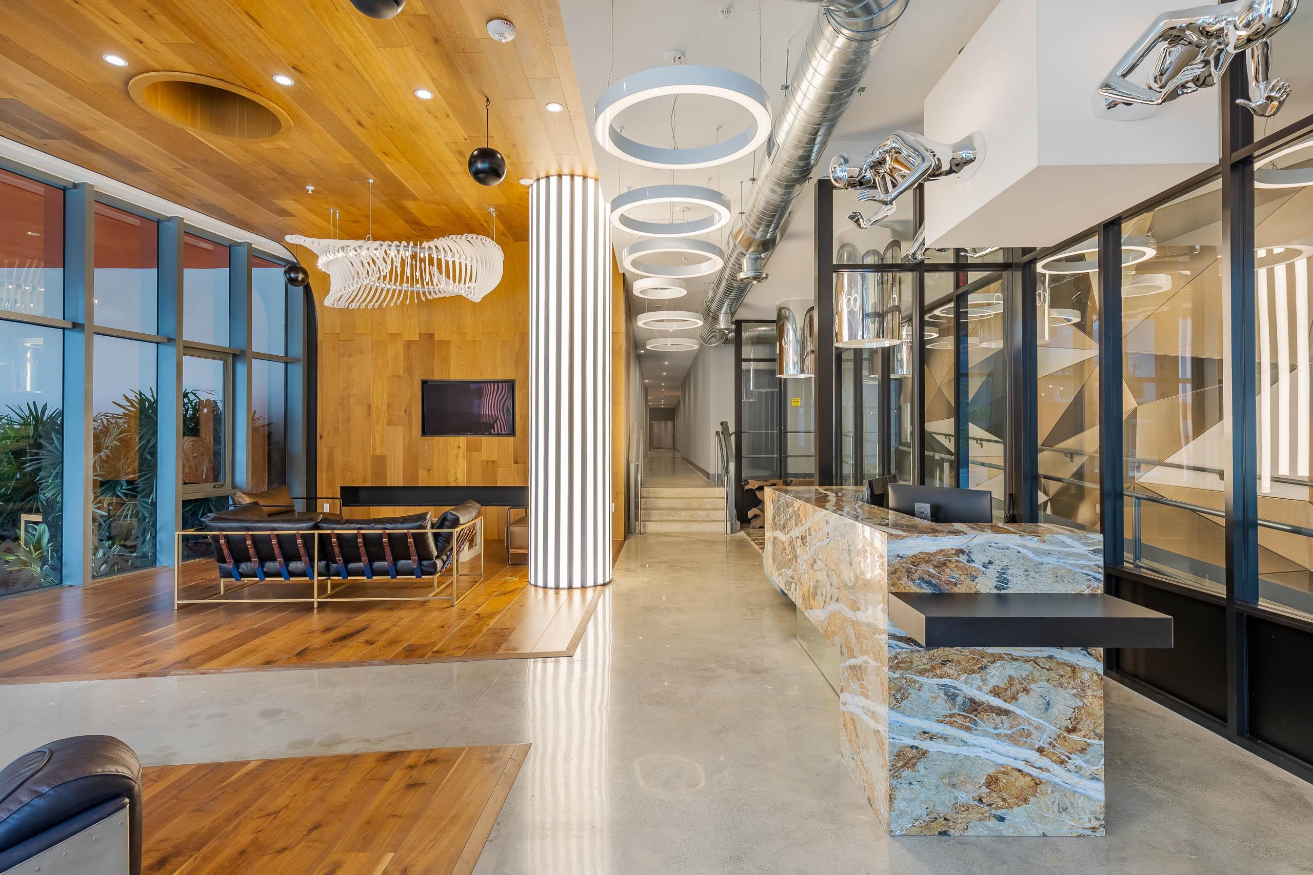 Interior view of the lobby at AMLI Midtown Miami apartments with wood accents and modern lighting with marble lobby desk 