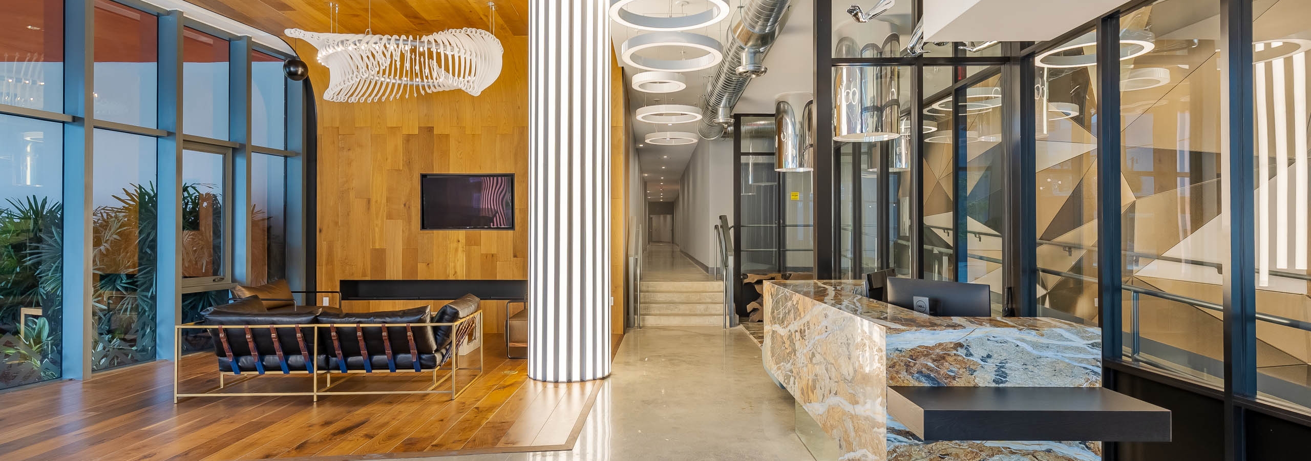Interior view of the lobby at AMLI Midtown Miami apartments with wood accents and modern lighting with marble lobby desk