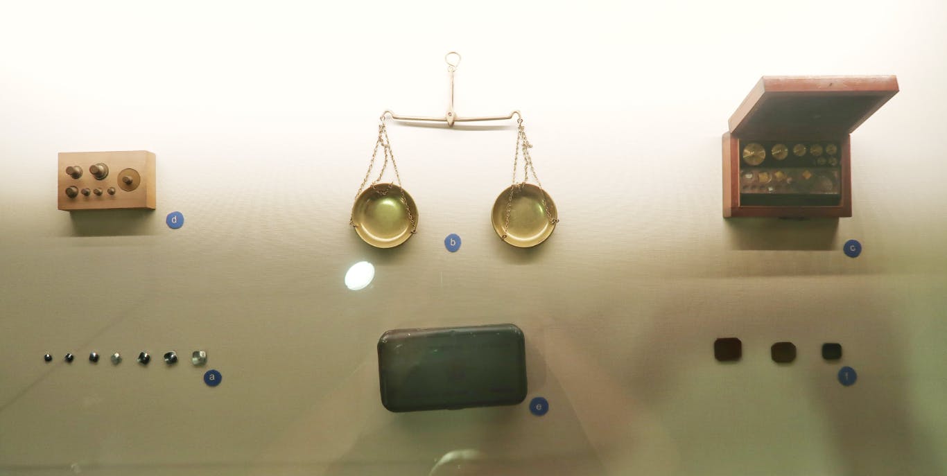A glass display case with small stones and a weighing scale set inside