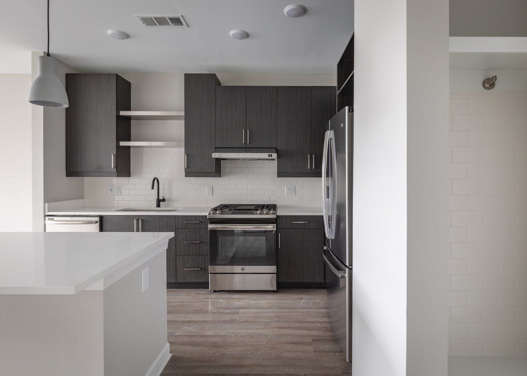 AMLI Westside kitchen with dark grey cabinets and white countertops with gas stovetop and premium stainless steel appliances